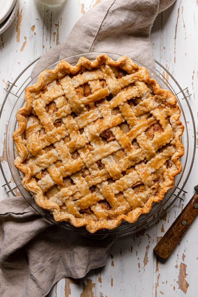 overhead shot of baked apple pie with lattice crust on grey napkin