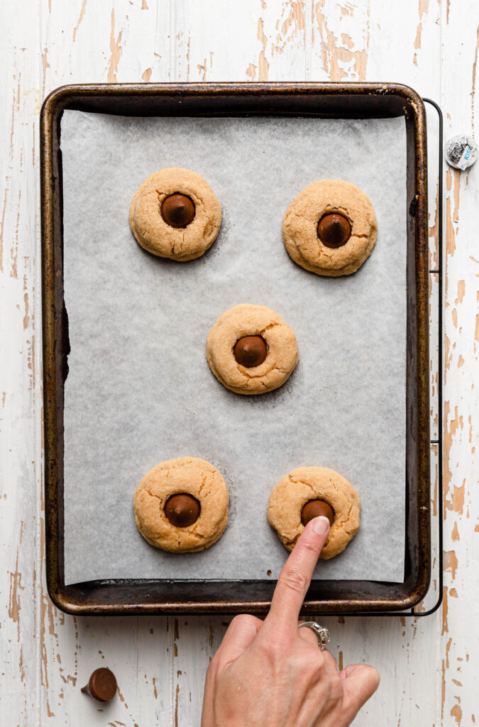 pressing hershey kiss into peanut butter cookie