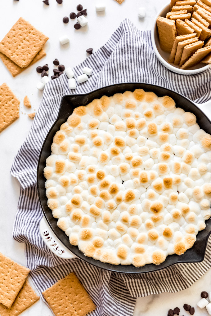 Toasted marshmallows in a skillet next to graham crackers.