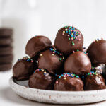 close up shot of oreo balls on white plate with milk