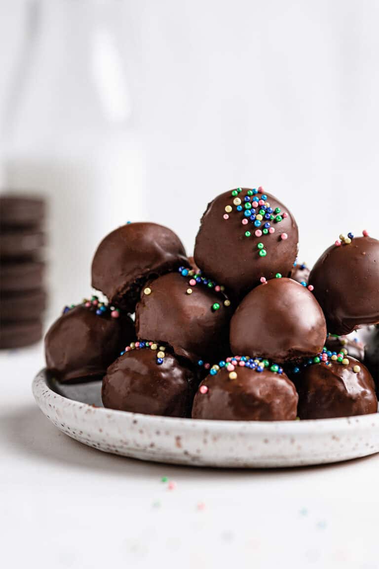 close up shot of oreo balls on white plate with milk