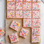 sugar cookie bars with pink frosting and sprinkles cut into bars