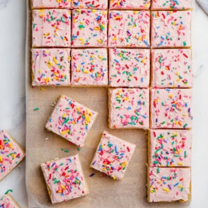 sugar cookie bars with pink frosting and sprinkles cut into bars