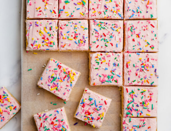 sugar cookie bars with pink frosting and sprinkles cut into bars