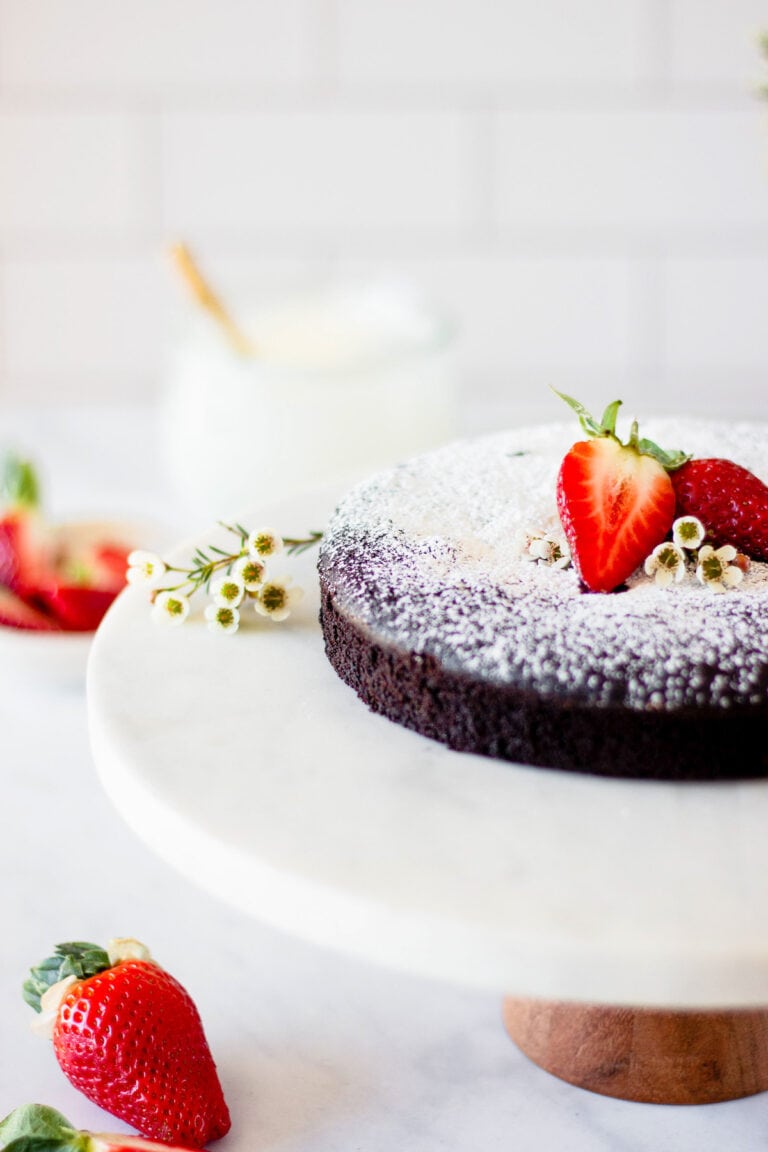 whole flourless chocolate cake on cake stand