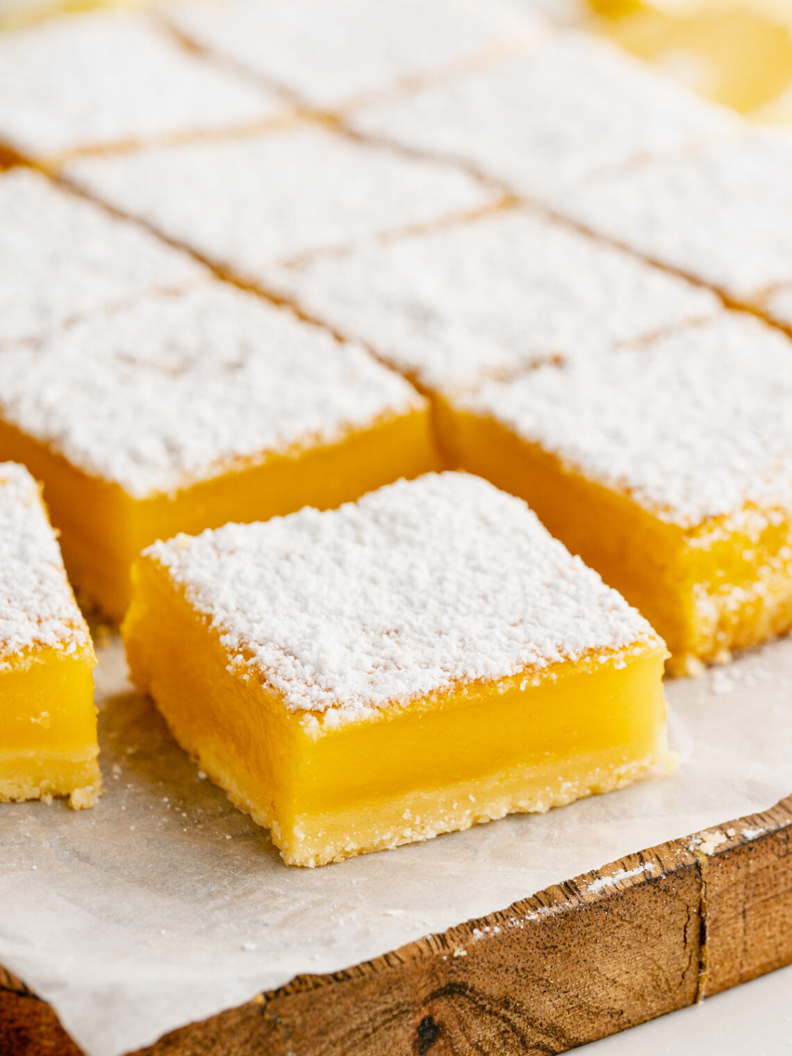 lemon bars on a parchment paper lined cutting board