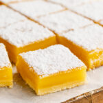 lemon bars on a parchment paper lined cutting board