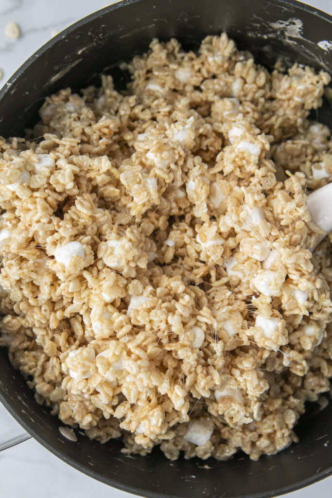 mixing brown butter rice krispie treat mixture in a pan