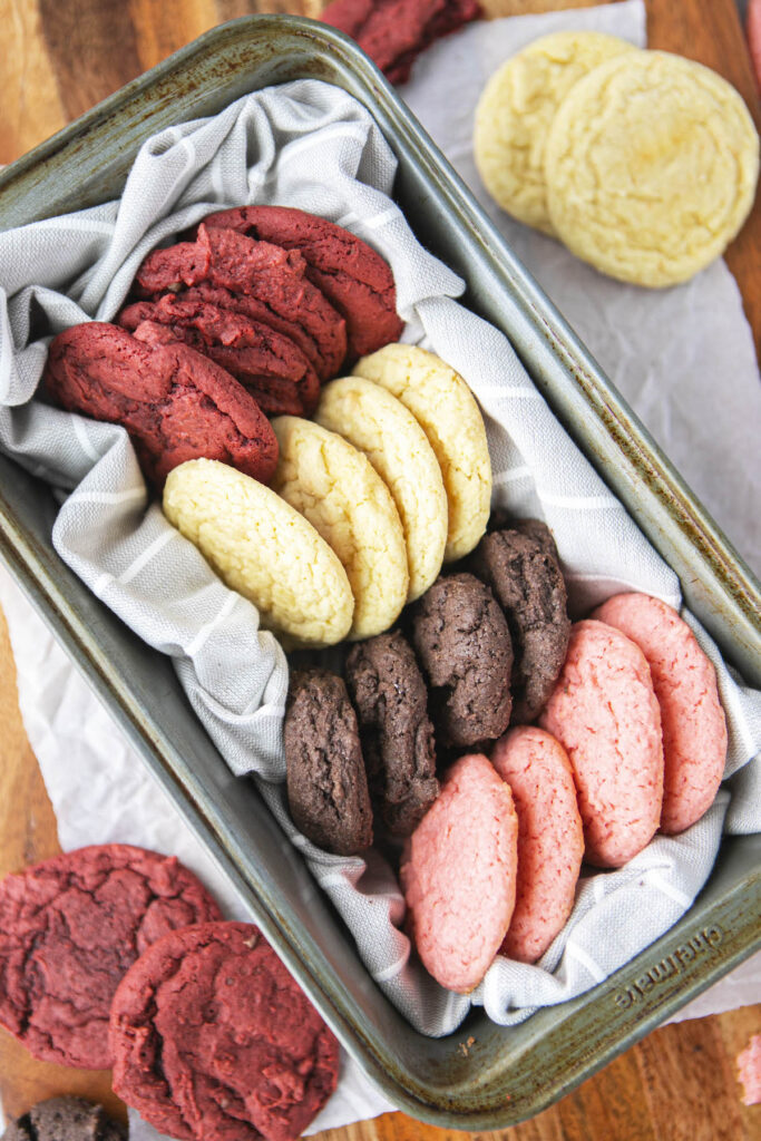 four different cake mix cookies in a metal tin