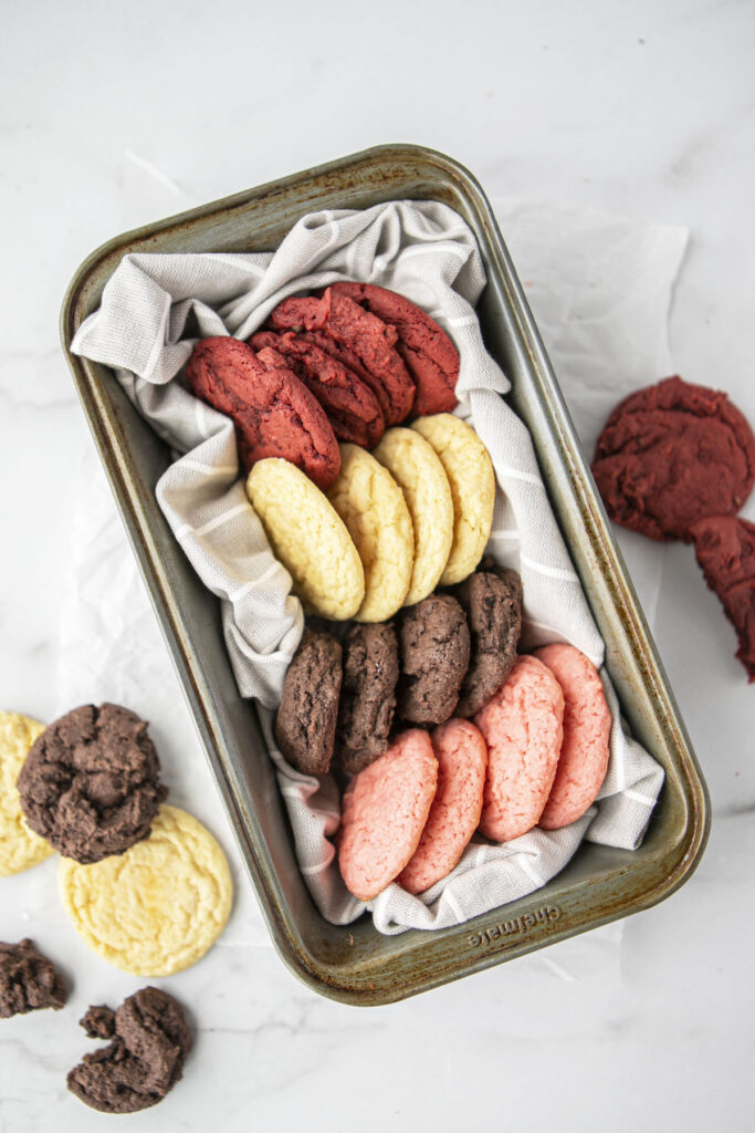 four different cake mix cookies in a metal tin