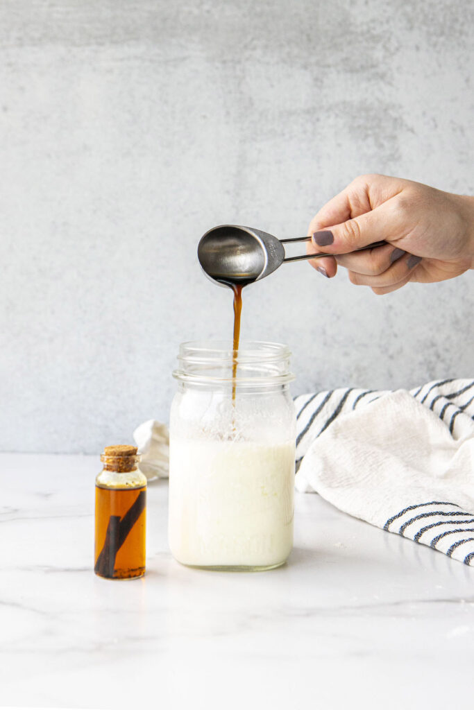 pouring vanilla into a jar of soured milk