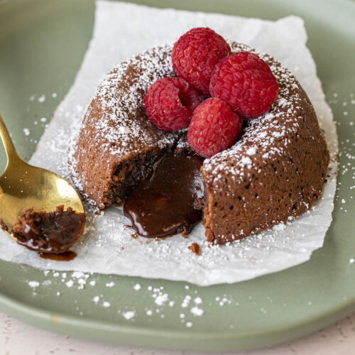 lava cake cut open with powdered sugar and raspberries on top