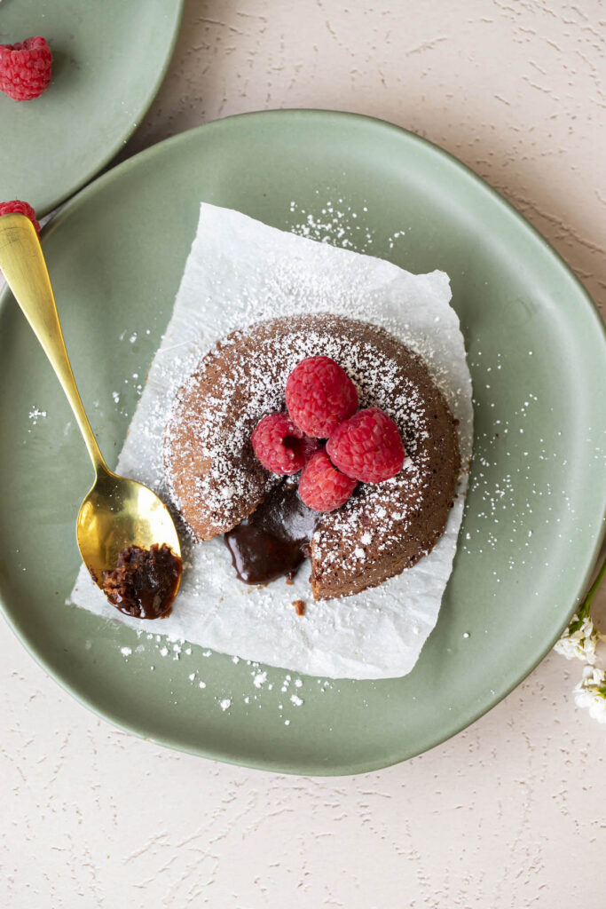 top down view of chocolate lava cake with powdered sugar and raspberries on top