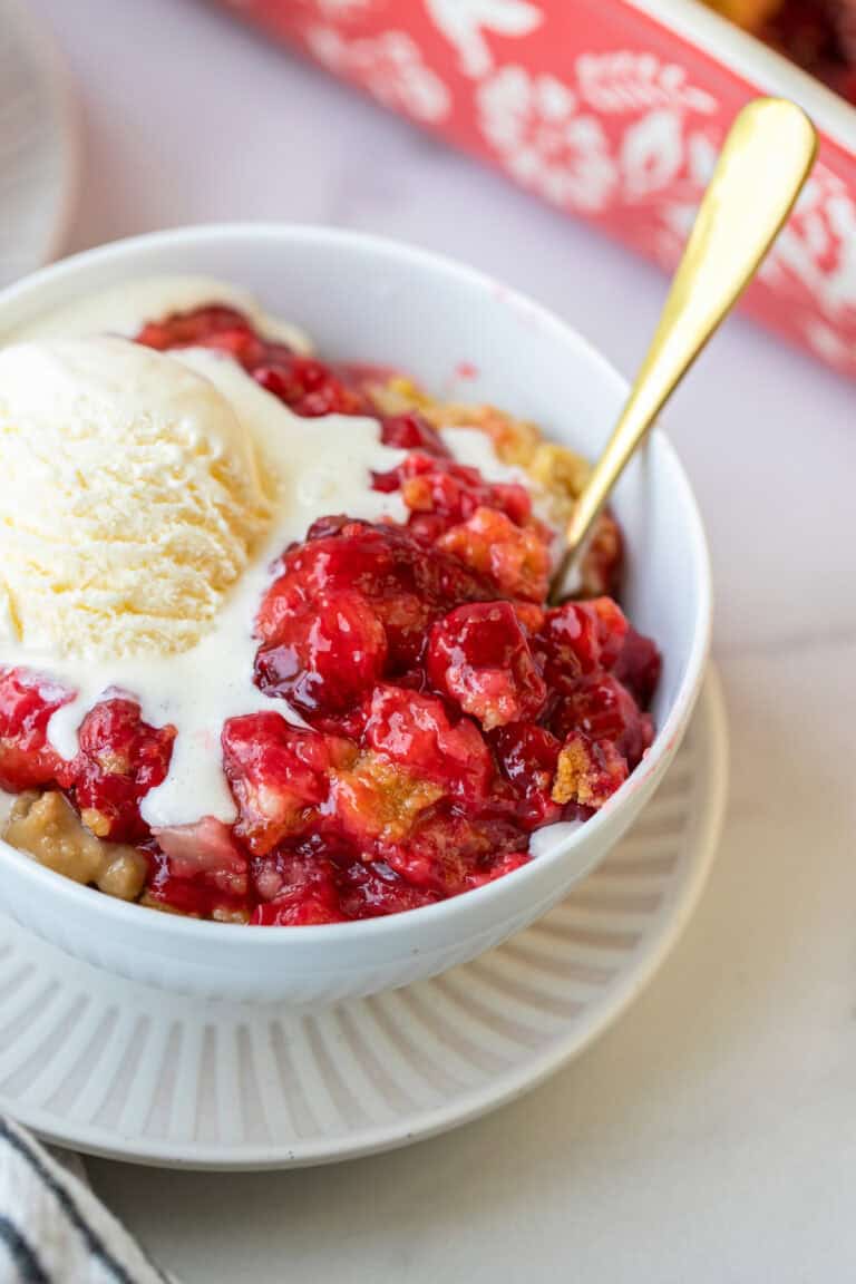 dump cake in white dish with ice cream on top