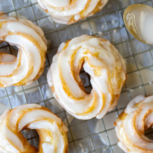 close up of crullers on parchment paper with icing