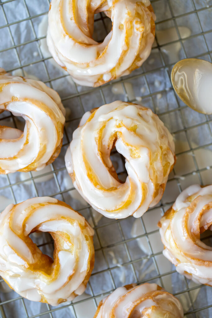 close up of crullers on parchment paper with icing