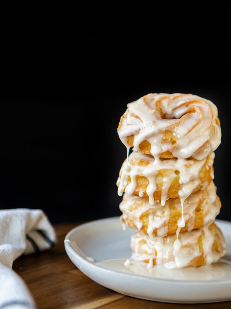 crullers stacked on top of each other with icing dripping down over them
