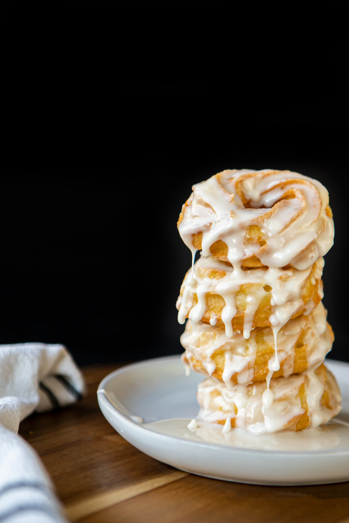 crullers stacked on top of each other with icing dripping down over them