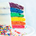 side view of rainbow cake with a slice cut out