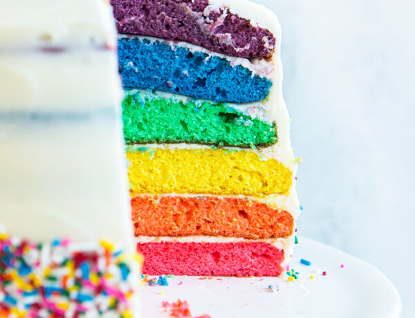 side view of rainbow cake with a slice cut out
