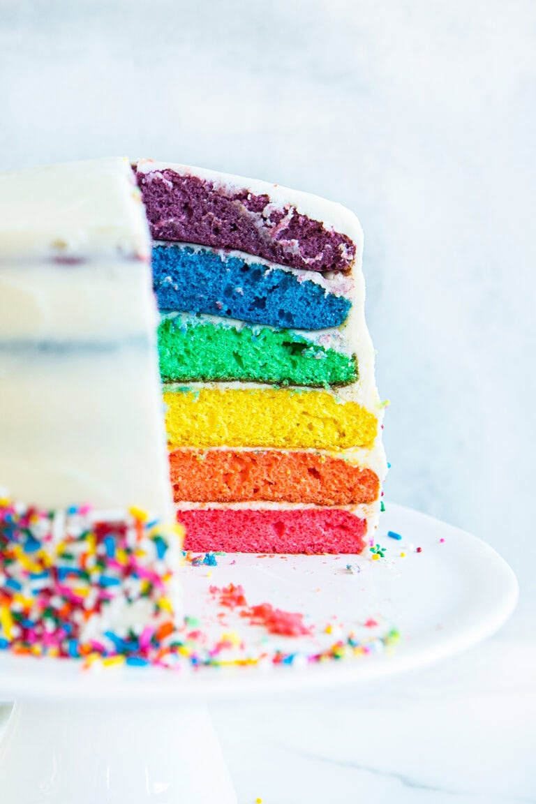 side view of rainbow cake with a slice cut out