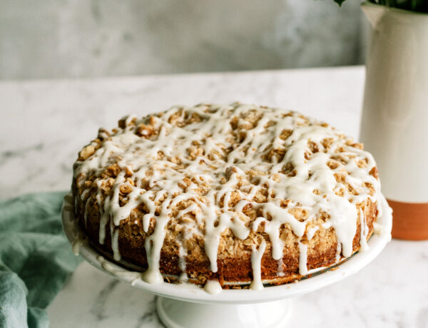 apple crumble cake with icing all on a cake stand