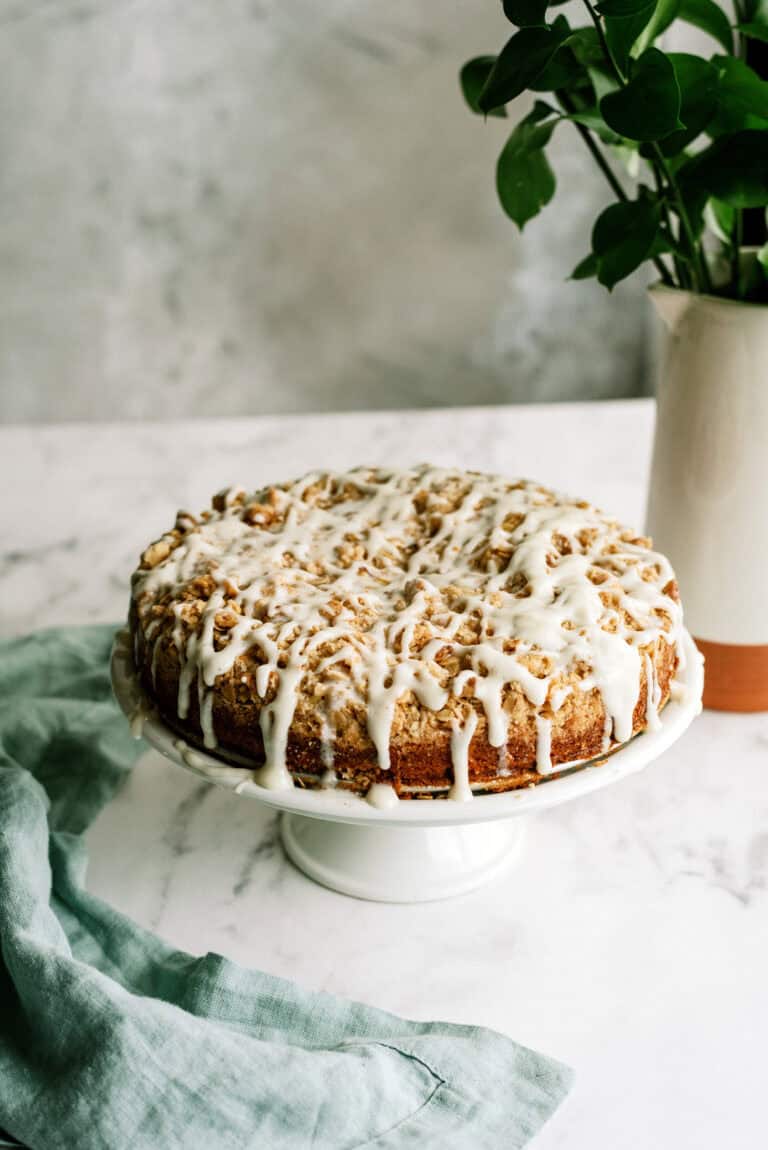 apple crumble cake with icing all on a cake stand