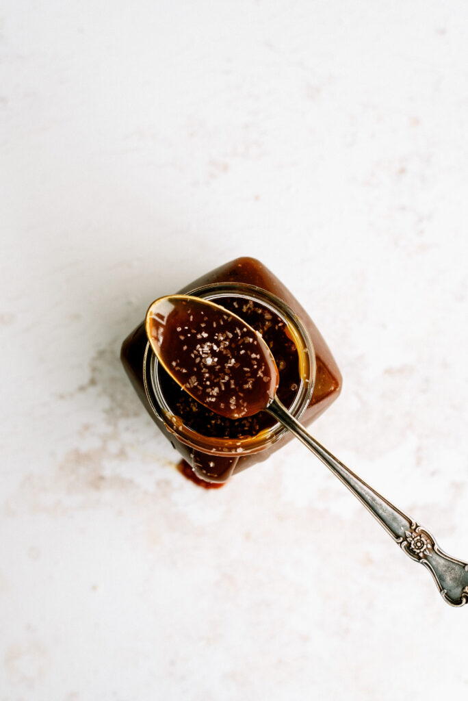 top down view of a spoonful of salted caramel resting on a jar