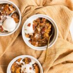 three white bowls with pumpkin cobbler and ice cream in them