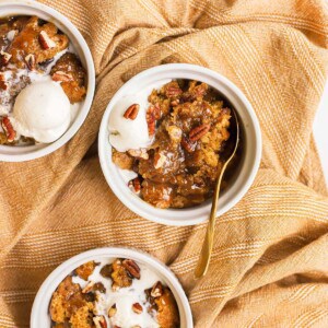 three white bowls with pumpkin cobbler and ice cream in them