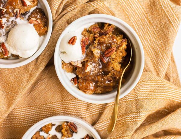 three white bowls with pumpkin cobbler and ice cream in them
