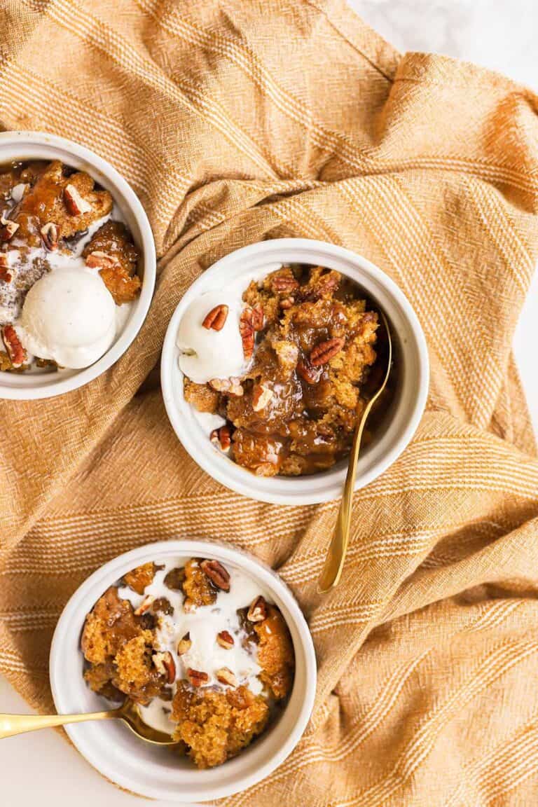 three white bowls with pumpkin cobbler and ice cream in them