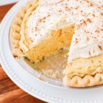 a pie plate full of pumpkin cream pie with a slice taken from it