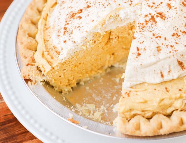 a pie plate full of pumpkin cream pie with a slice taken from it