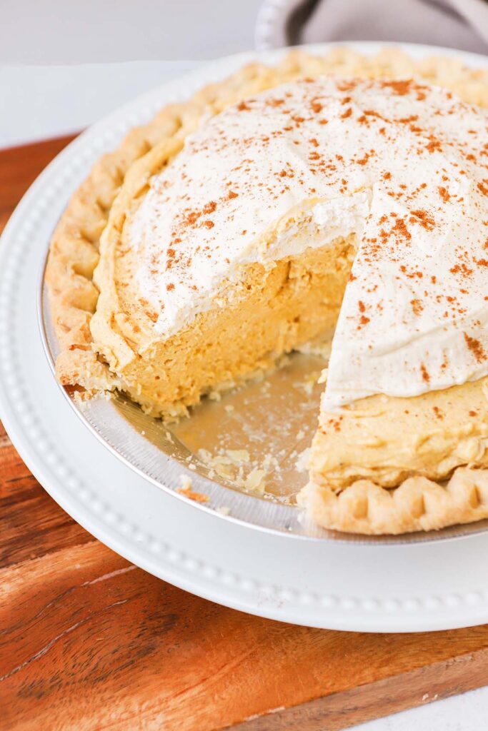 a pie plate full of pumpkin cream pie with a slice taken from it