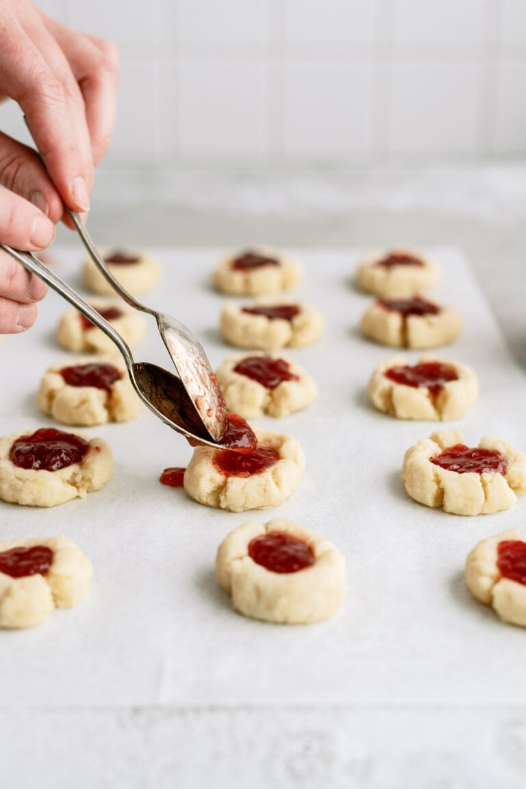 spooning jam into thumbprint cookies