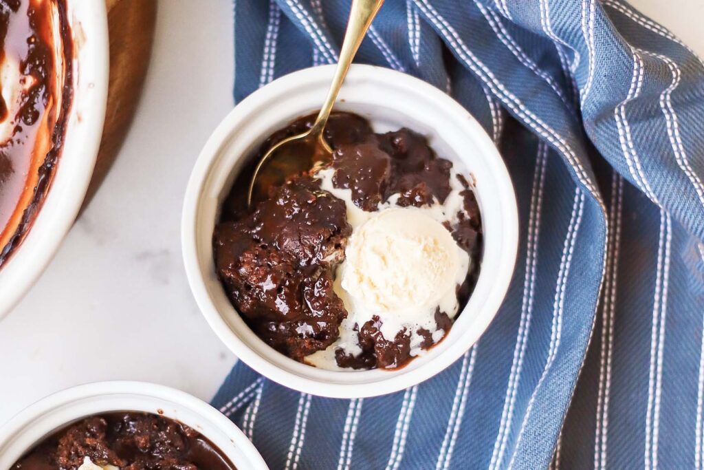 Overhead photo of chocolate cobbler in a bowl with a scoop of vanilla ice cream