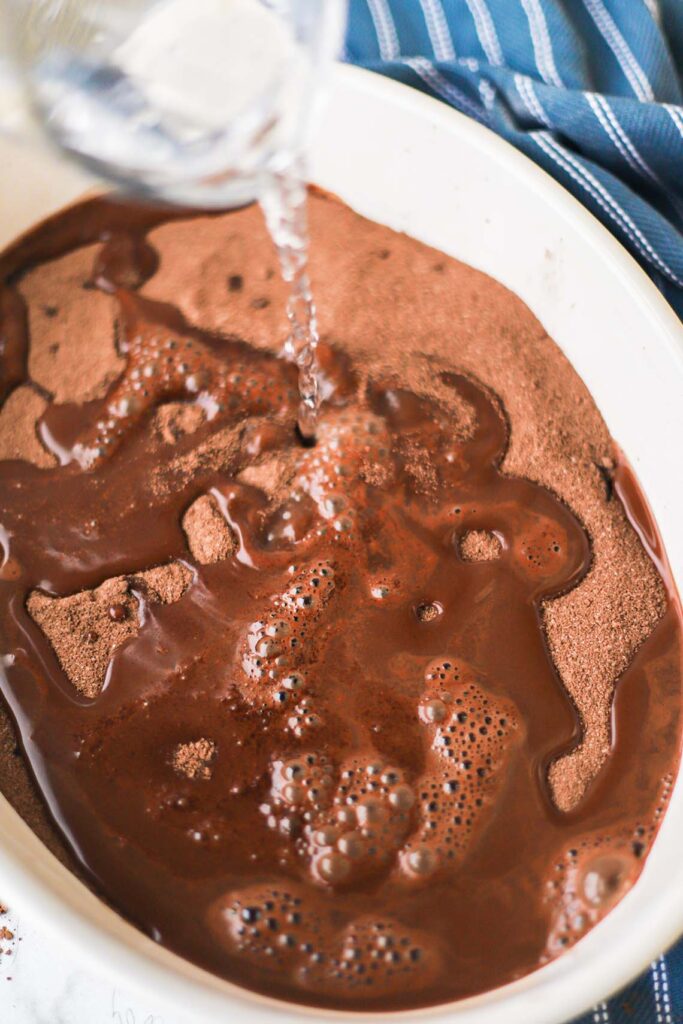 Pouring hot water over chocolate cobbler batter