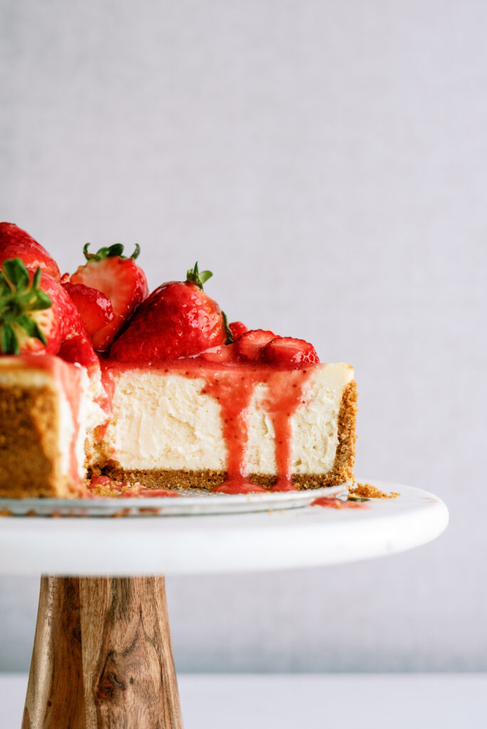 strawberry cheesecake with slices taken out on a cake stand