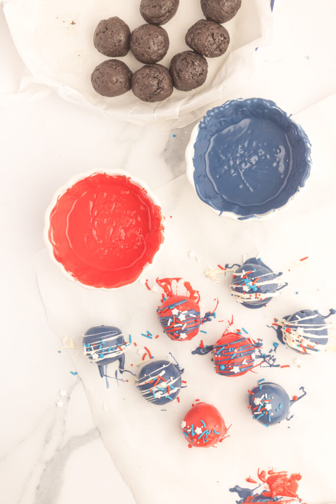 A table with red, white and blue decorations and a bowl of chocolate covered balls.