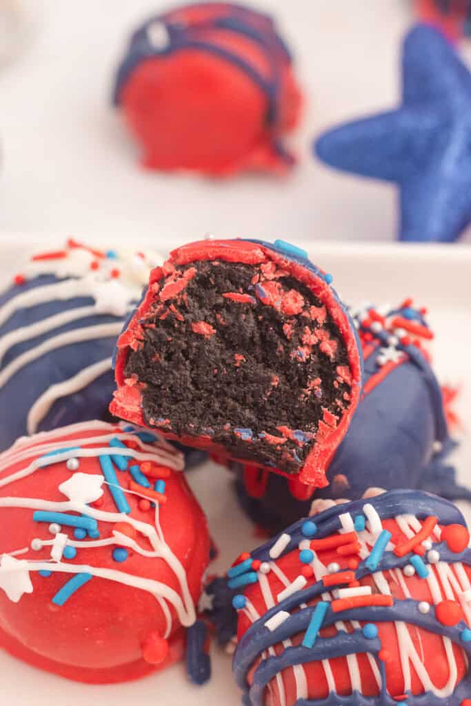A plate of red, white and blue oreo balls with one having a bite taken out of it