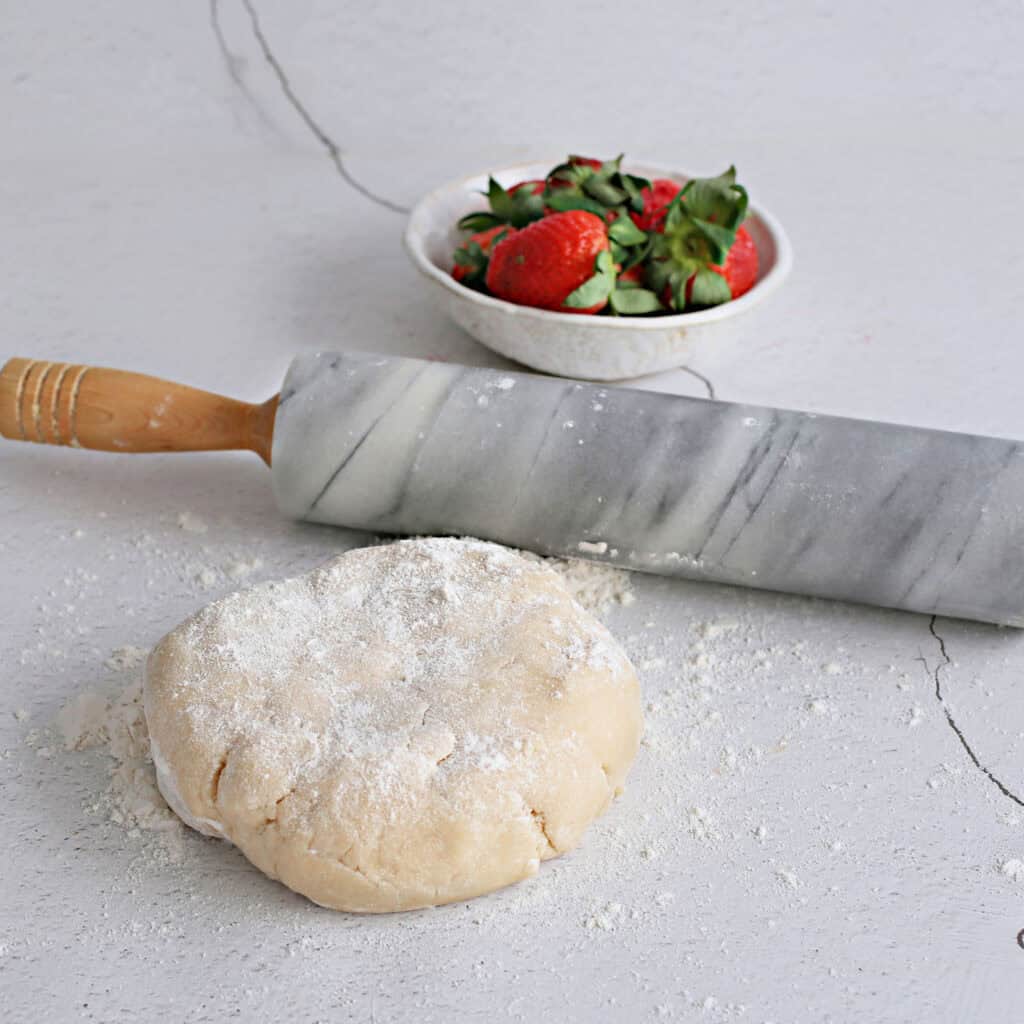 The image shows pastry squares with strawberry jam filling on a baking sheet, ready to be baked into a tasty dessert.