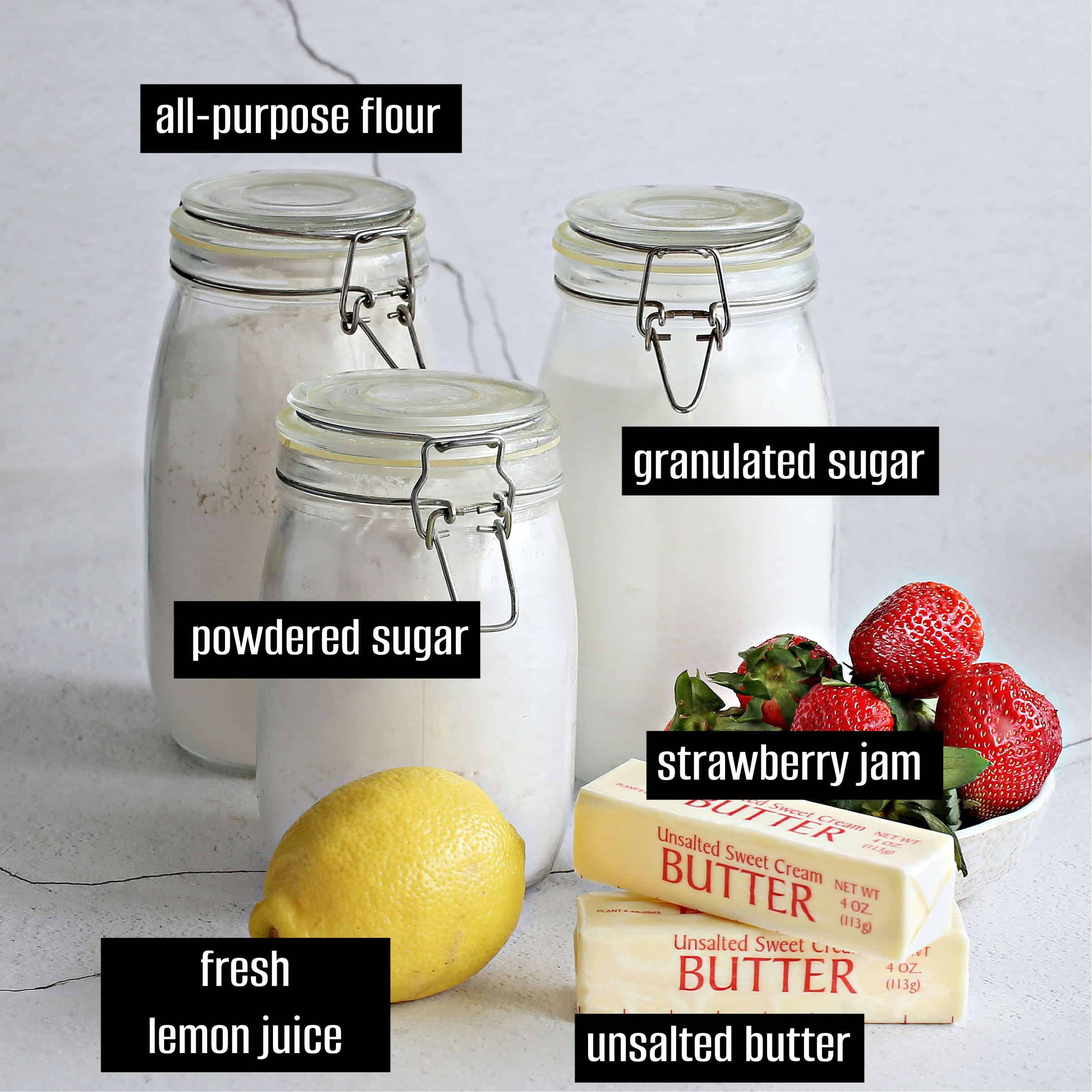 Assorted baking ingredients including flour, sugars, butter, lemon juice, and strawberry jam.